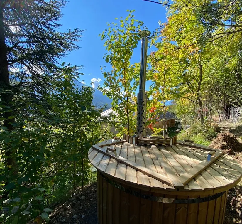 Le bain nordique en bois installé dans le jardin, entouré d'arbres