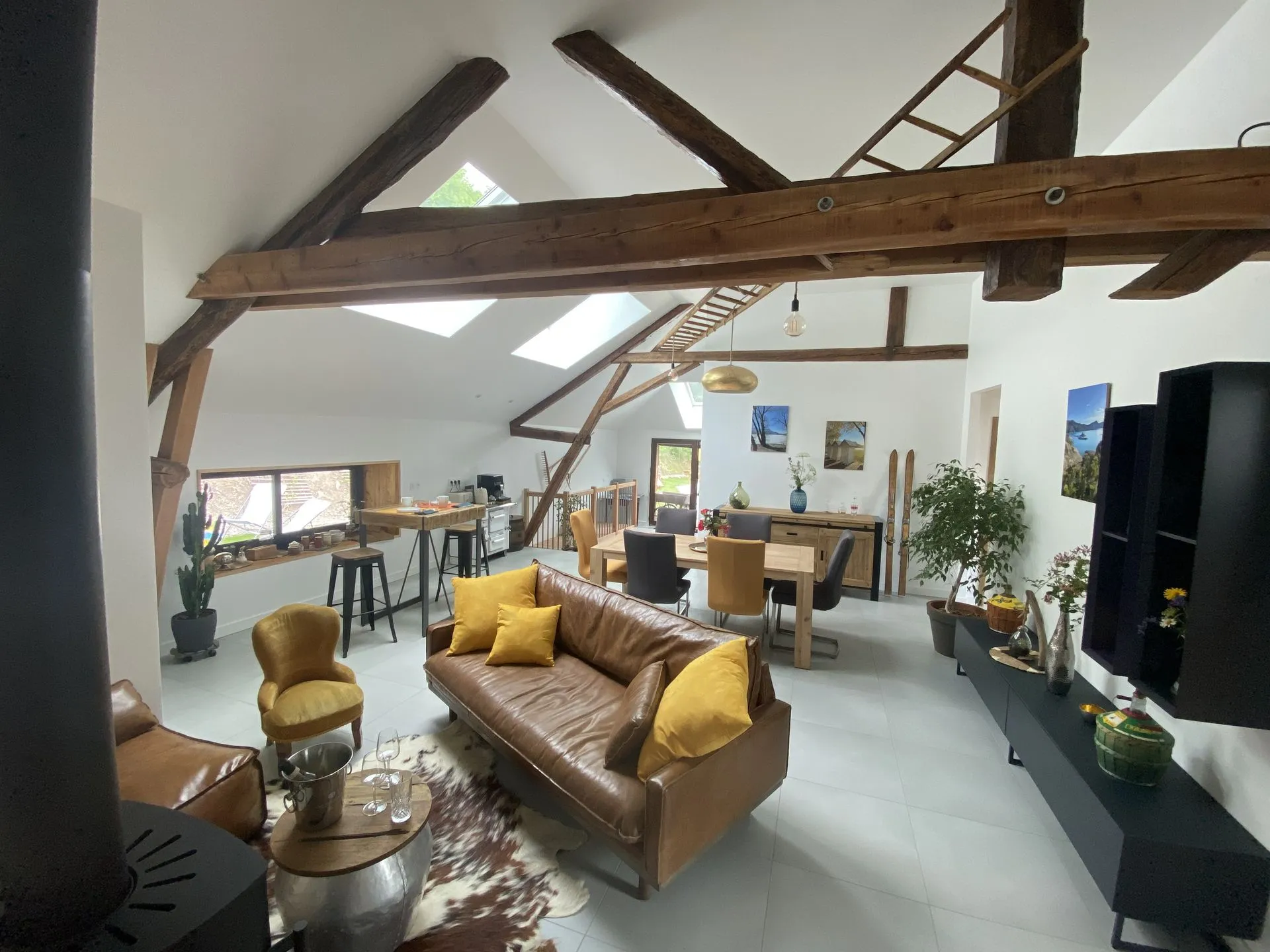 La salle de réception du gîte, avec son coin salon autour du poêle à bois sous les poutres apparentes
