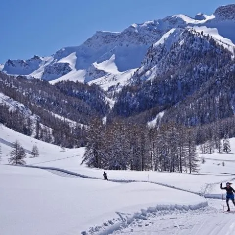 Deux skieurs de fond sur une trace damée, au pied d'un cirque enneigé